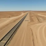 Railway track exposed to sandstorms and shifting desert dunes in Sahara environment