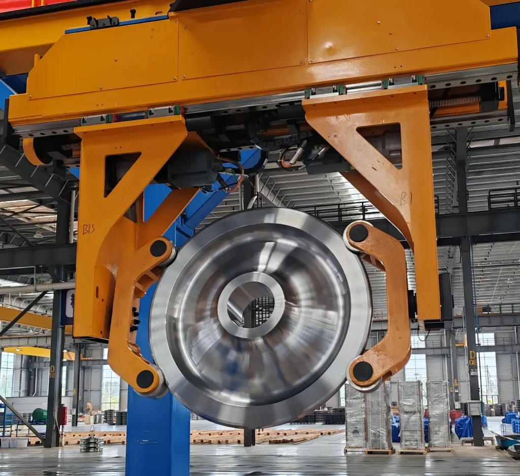 Gantry robot lifting a railway wheel inside a production workshop