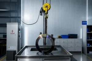 Railway Component Inspection Large forged steel ring undergoing magnetic particle inspection in a modern industrial NDT workshop with central conductor magnetic testing equipment.